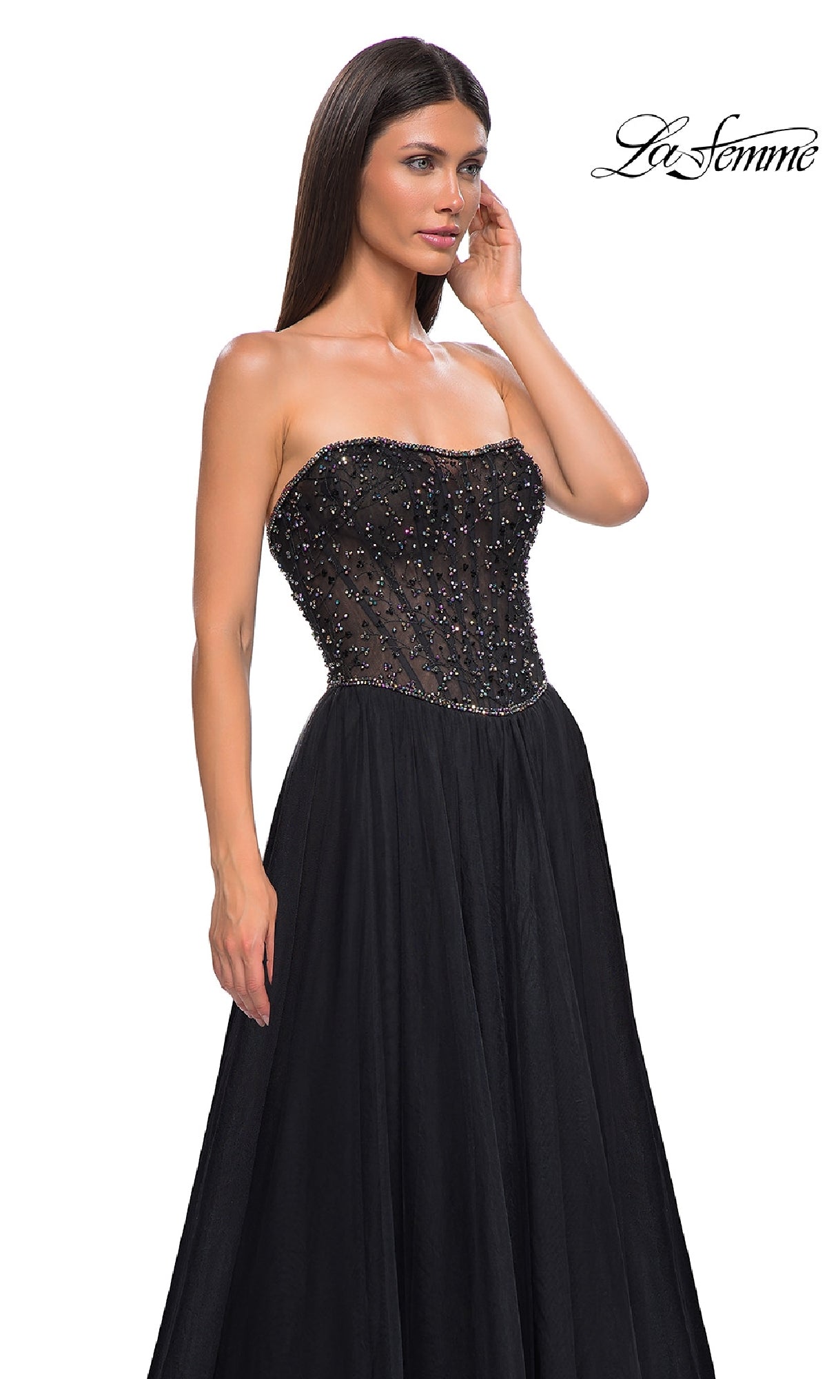 A woman models the Strapless Long Black Prom Ball Gown: La Femme 32856, featuring a beaded semi-sheer bodice and flowing skirt, standing against a white background with the La Femme logo in the corner.